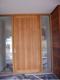 Modern light-timber entry door with glass side panels