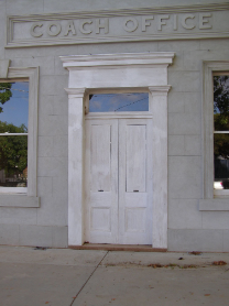 Restored heritage white double doors under coach office lintel