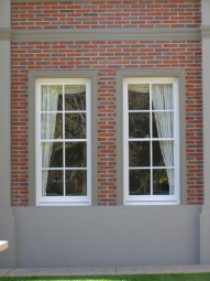 Pair of white timber double-hung windows in red brick wall